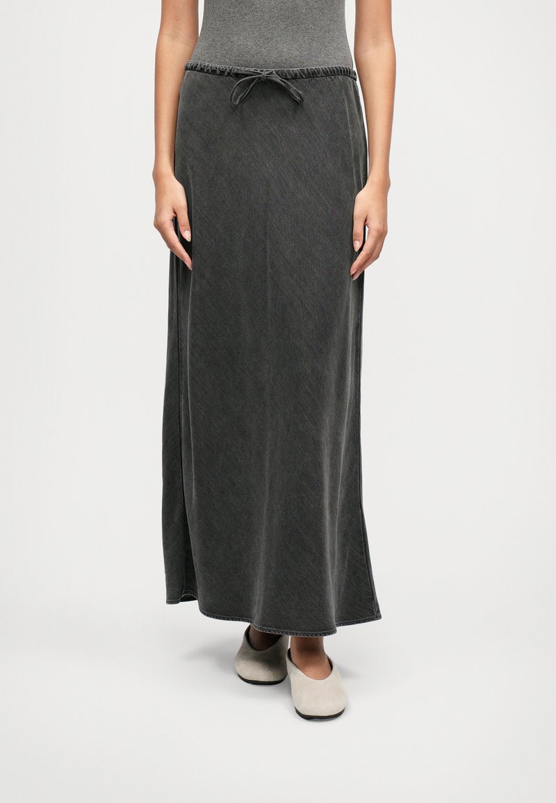 Falda maxi en gris oscuro, hecha de una tela suave con cintura elástica ajustable. Presenta un diseño simple y recto con una textura lisa.