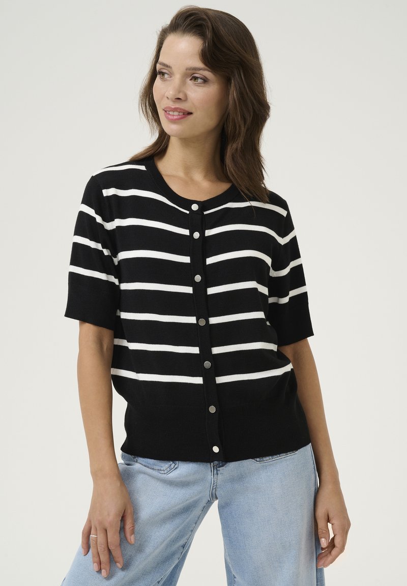 Schwarz-weiß gestreifter Kurzarm-Cardigan mit Rundhalsausschnitt, großen Knöpfen und einem gerippten Saum, kombiniert mit hellblauen Jeans.