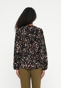 Langærmet bluse i sort med et struktureret abstrakt mønster i cremede og blush nuancer, med en afslappet pasform og en let samlet rygdesign.