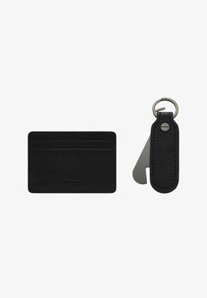 Porte-cartes en cuir noir avec une texture lisse et des bords surpiqués, accompagné d'un porte-clés assorti avec un accent en métal et un anneau.
