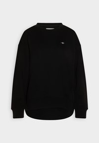 Schwarzer Sweatshirt mit Rundhalsausschnitt und langen Ärmeln. Mit einem kleinen Emblem auf der Brust. Weiche Textur, lockere Passform und gerippte Bündchen.