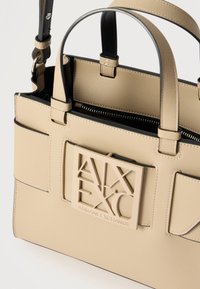 Τσάντα χειρός από μπεζ δέρμα με διπλές λαβές, μπροστινή τσέπη και πλακέτα με το λογότυπο Armani Exchange στο μπροστινό μέρος.