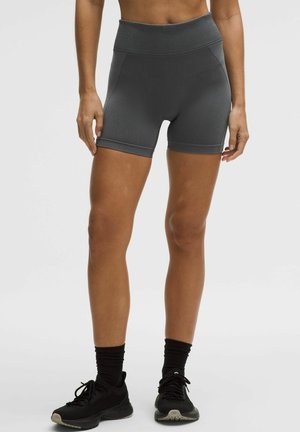 Vysoký pás sivých športových šortiek s hladkou, elastickou textúrou, vybavených rebrovaným pásom a dĺžkou po polovicu stehien.