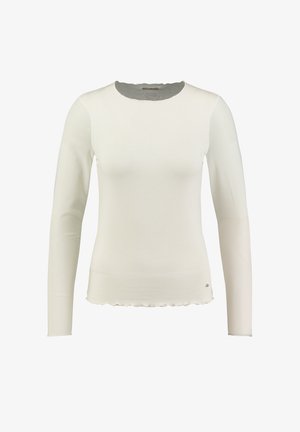 Biała bluzka z długim rękawem, wykonana z fakturowanej tkaniny, z falbaniastym dołem i okrągłym dekoltem. Posiada mały akcent logo na dole.