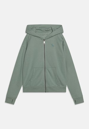 Grøn, zip-up hoodie lavet af blød, tekstureret stof. Den har en kengurulomme, ribbede manchetter og et lille broderet logo på brystet.