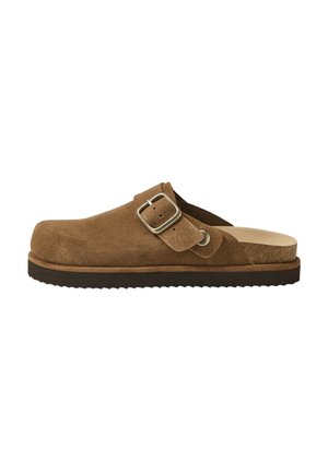 Bruine suède slip-on klomp met verstelbare zilveren gespsluiting en gestructureerde zwarte zool, ontworpen voor casual gebruik.