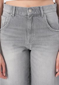 Grå denimjeans med høyt liv, rette ben, frontlommer og knappelukking. Stoffet har en subtil tekstur og en falmet finish.