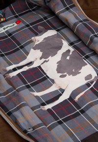 Brown leather jacket with gray and black checkered lining featuring a large, realistic illustration of a black-and-white cow.