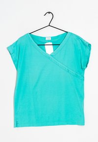 T-shirt turchese a maniche corte con scollo a V, design con incrocio frontale, realizzato in tessuto leggero, con spacchi laterali per facilitare il movimento.