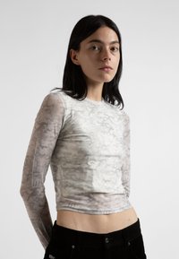 Langermet topp i lys grå med et subtilt mønster, laget av et gjennomsiktig materiale, med en tettsittende design og rund halslinning.