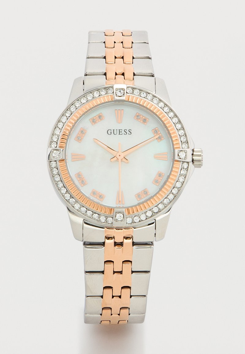 Ρολόι Guess με ασημί και ροζ χρυσό μεταλλικό μπρασελέ, στεφάνη με κρύσταλλα, λευκό καντράν και δείκτες καθώς και δείκτες ωρών σε ροζ χρυσό.