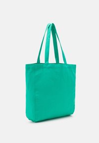 Zöld szövet bevásárlótáska, két lapos fogantyúval, téglalap alakú, sima felülettel; további minták vagy fémalkalmazások nem láthat�ók.