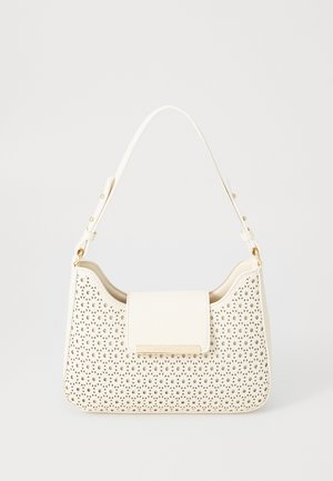 Kremowa torebka z ozdobnym kwiatowym wzorem do perforacji, prostokątną klapką, złotą tabliczką z logo oraz regulowanym paskiem na ramię z klamrą.