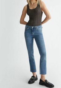 Brun ribbade linnen, ljusblå raka jeans med fransad fåll, svarta loafers med guld detaljer.