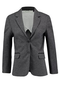 Blazer a scacchi bianco e nero con chiusura a singolo bottone, revers a punta e tasche laterali. Fodera interna liscia, vestibilità su misura.