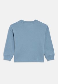 Világoskék hosszú ujjú pulóver kerek nyakkal, kissé rövidített fazonban és bordázott mandzsettával. Puha tapintású, minimalista stílusú.