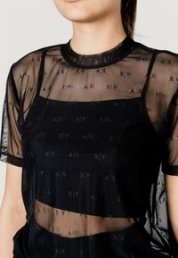 Top negro transparente con escote cuadrado, mangas cortas y un patrón texturizado de logotipos repetidos. Ligero, con un aspecto de capas.