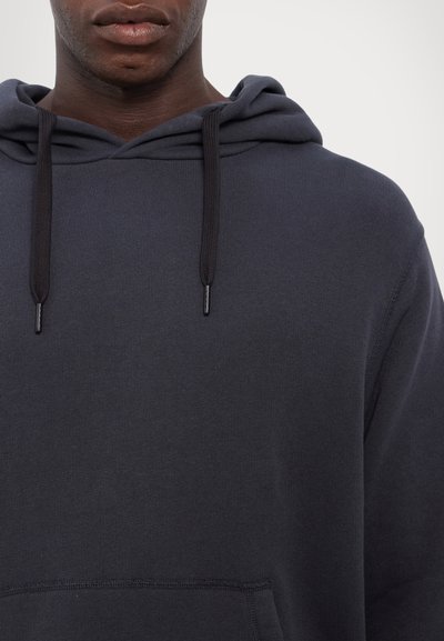 Mørkegrå hettegenser med frontlomme, snorhette og ribbestrikkede mansjetter. Glatt tekstur og minimalistisk design uten synlige logoer.
