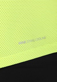 Tela de malla amarilla texturizada con pequeños agujeros que presenta un logo de "NIKE ZONAL COOLING", combinada con una tela negra lisa debajo.