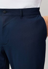 Pantalones azul marino con un acabado liso y texturizado, que cuentan con un cierre de botón seguro, bolsillos laterales y un detalle de costura mínima.