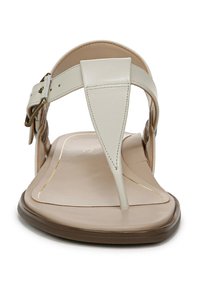 Beige teen sandaal met een soepel leren bovenwerk, een platte bruine zool en een diagonale strap ontwerp. Voorzien van een gouden gesp voor aanpassing.