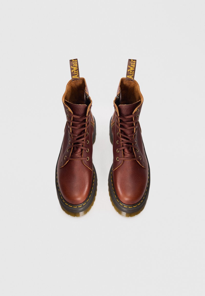 Bottes de cheville en cuir marron avec des orteils arrondis, des coutures jaunes et un col en cuir marron texturé. Comprend des œillets renforcés et une languette en boucle.