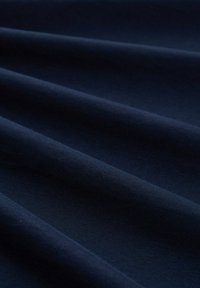 Granatowy materiał o gładkiej teksturze, z subtelnymi zmarszczeniami i jednolitym wyglądem, wskazujący na miękki i elastyczny surowiec.