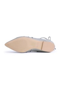 Zapato plano gris con punta afilada, parte superior texturizada y suela de goma lisa. Incluye cordones finos y un tacón bajo.