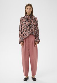 Bluse med leopardprint i pink og sort med flæsekrave, stylet med højtaljede, løstsiddende pink bukser og sorte ballerinasko.
