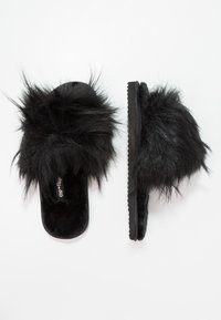 Black slide slippers made of soft fur material with a textured sole. Features a plush fuzzy upper and a flat design for comfort.
