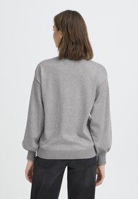 Hall grey kudum, millel on pikad, puhvatusvarrukad ja soonikkoes. Seljal on lihtne, siledisain, ilma mustrite või kaunistusteta.