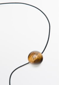 Halskæde med en rund brun træperle på en tynd sort snor, der viser en glat overflade og subtile årer. Minimalistisk design.