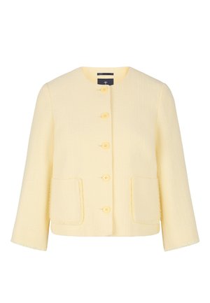 Yellow tweed jacket with a round neck, button front closure, two patch pockets, and frayed edges on the sleeves and hem.