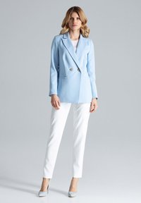 Jasnoniebieska podwójnie zapinana marynarka z dwoma złotymi guzikami, z klapami, połączona z białymi slim-fit spodniami i jasnoniebieskimi szpilkami.
