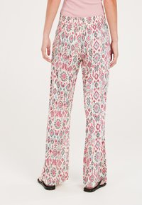 Vloeiende, gemusterde broek met een elastische tailleband. Heeft een kleurrijk geometrisch patroon op een lichte achtergrond. Gemaakt van lichte stof.