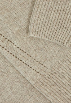 Beiger Strickpullover-Stoff mit gerippten Kanten. Enthält ein strukturiertes Muster und kleine Lochdetails entlang einer Naht. Weicher, gemütlicher Look.