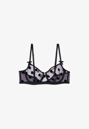 Soutien-gorge en mesh noir transparent avec motif à pois, soutien-gorge à armatures, bretelles réglables et nœuds décoratifs aux extrémités des bretelles.