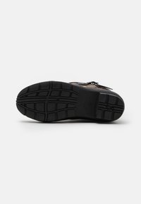 Semelle de chaussure en caoutchouc noir présentant un motif de semelle avec des rainures profondes pour l'accroche, des bords lisses et un minimum de marquage en relief.