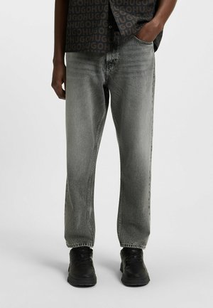 Gray denim jeans featuring a loose fit, straight leg design, and subtle fading. Paired with black sneakers for a casual look.