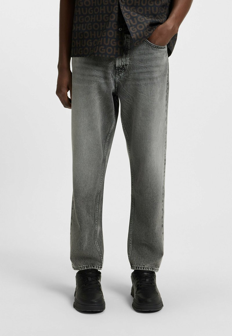 Jeans in denim grigio con vestibilità ampia, design a gamba dritta e una leggera sfumatura. Abbinati a sneakers nere per un look informale.