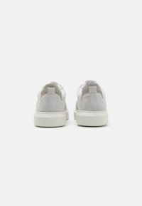 Adidași din piele albă și nubuc gri cu o talpă texturată, un guler căptușit și un design minimalist. Toc întărit pentru durabilitate.