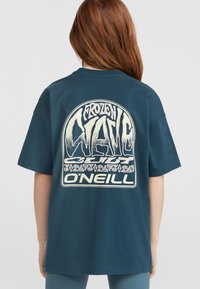 Tamsiai žalia medvilninė marškinėliai su dideliu kreminės spalvos grafiniu piešiniu ant nugaros, kuriame yra tekstas "FROZEN WAVE" ir prekės ženklas "O'NEILL" apačioje. Trumpomis rankovėmis.