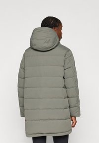 Pilkas pūkinis paltas su kapišonu, turintis horizontaliai siuvinėtas juostas, vidutinio ilgio kirpimą ir lygią, matinę tekstūrą.