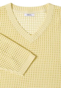 Pull jaune pâle en maille ajourée avec col en V, poignets et col côtelés, avec une étiquette de marque "CECIL" à l'encolure.