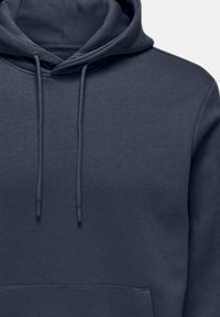 Hoodie gris foncé en mélange de coton doux. Dispose d'une capuche avec cordon de serrage, d'une poche avant et de poignets côtelés avec une texture lisse.