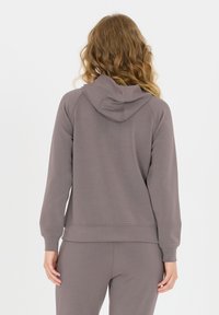 Grauer Kapuzenpullover mit lockerer Passform, Kapuze, gerippten Bündchen und Saum. Aus weichem Material gefertigt, mit einem dezenten Logo auf dem Rücken.