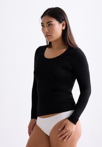 Zwarte, aansluitende top met lange mouwen en ronde halslijn, gemaakt van een gladde stof, gecombineerd met witte onderkleding. Eenvoudig ontwerp, zonder zichtbare patronen of hardware.