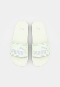 Ljust gröna halkskydd med en mjuk yta, med en bred rem som har en lila "PUMA"-logotyp och en liten lila kattlogotyp på varje sida.