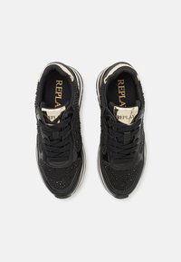 Czarne trampki z fakturowaną cholewką, ozdobione małymi ćwiekami. Posiadają czarne sznurowadła, wyściełane wsparcie kostki oraz srebrny akcent.