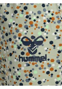 Groene stof met een gespikkeld patroon in oranje, grijs, zwart en lichtgroene tinten; heeft een donker logo van "hummel" en grafisch ontwerp.